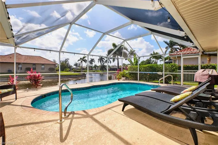 Swimming pool featuring a patio, glass enclosure, a sunroom, grilling area, and a water view