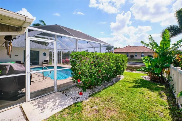 View of swimming pool featuring glass enclosure, a sunroom, patio surround, a lawn, and area for grilling