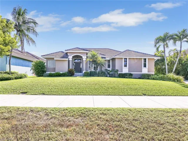 View of front of home with stucco siding, a front yard, and a tile roof