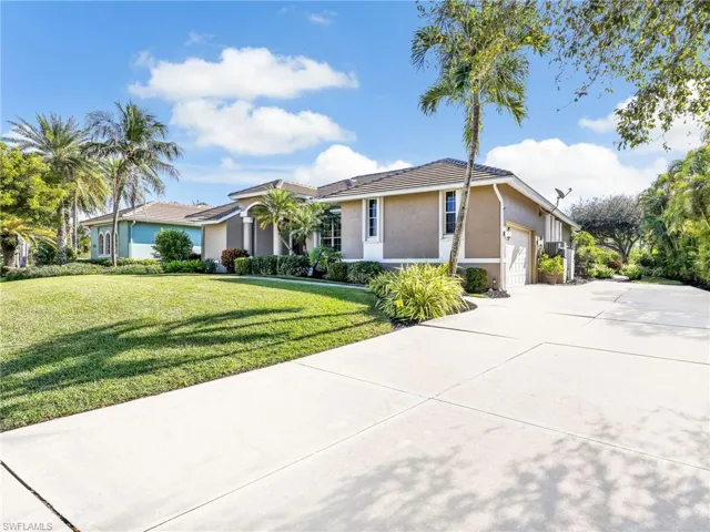 Single story home with stucco siding, a front yard, concrete driveway, a tiled roof, and a garage