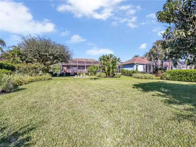 View of grassy yard with a sunroom and a lanai