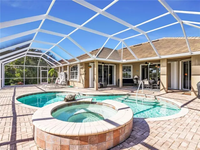 View of pool featuring a sunroom, a lanai, a pool with connected hot tub, and a patio area