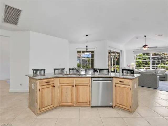 Kitchen with light brown cabinetry, dishwasher, a breakfast bar area, and plenty of natural light