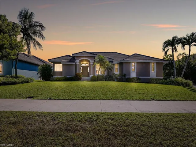 View of front of property with a lawn, stucco siding, and a tiled roof