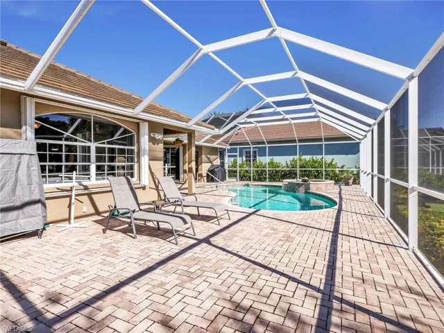 Outdoor pool featuring a patio, a sunroom, and glass enclosure