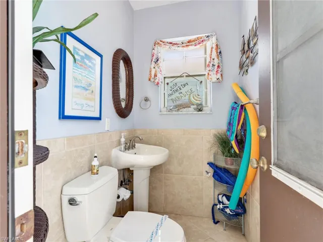 Half bathroom with tile walls and a wainscoted wall