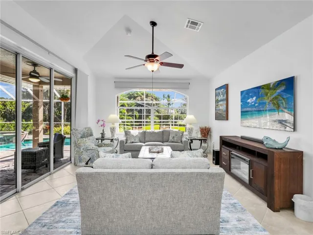 Living area featuring light tile patterned flooring, a ceiling fan, and a sunroom