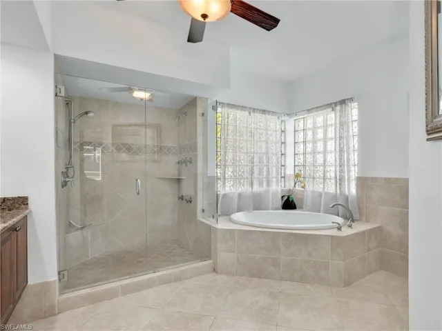 Full bath featuring a bath, a shower stall, vanity, light tile patterned flooring, and ceiling fan