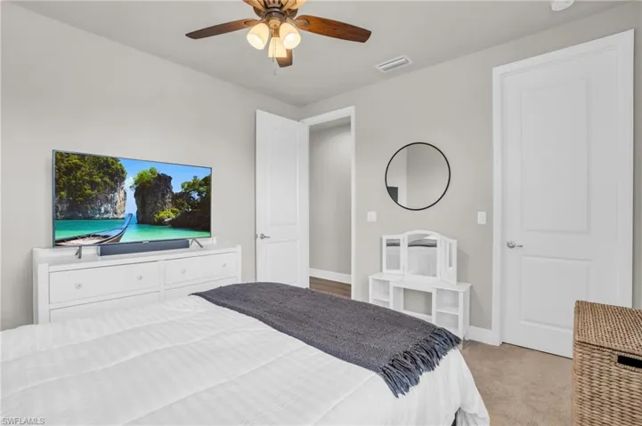 Bedroom with ceiling fan and light colored carpet