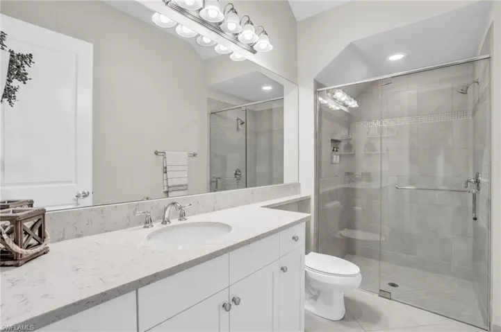 Bathroom with an enclosed shower, tile flooring, toilet, and vanity with extensive cabinet space