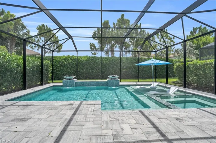 View of swimming pool with a patio area, glass enclosure, and an in ground hot tub