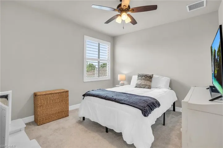 Bedroom with ceiling fan and light carpet