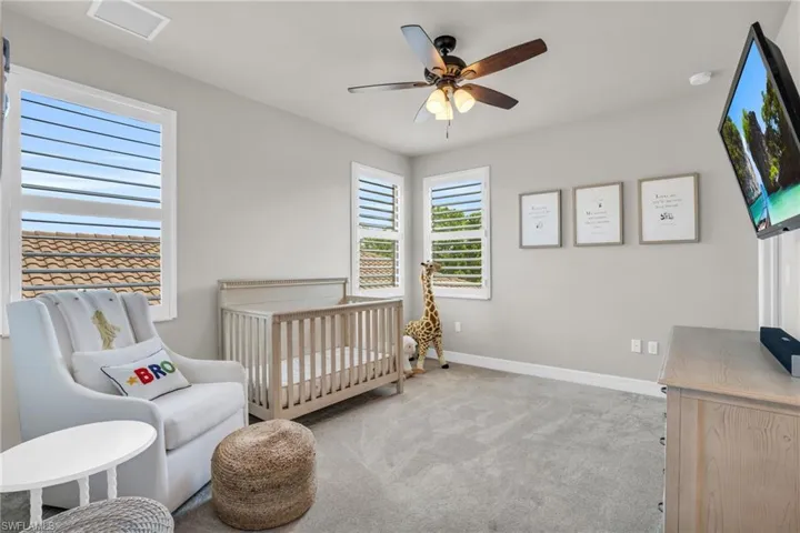 Bedroom featuring carpet flooring, a nursery area, and ceiling fan