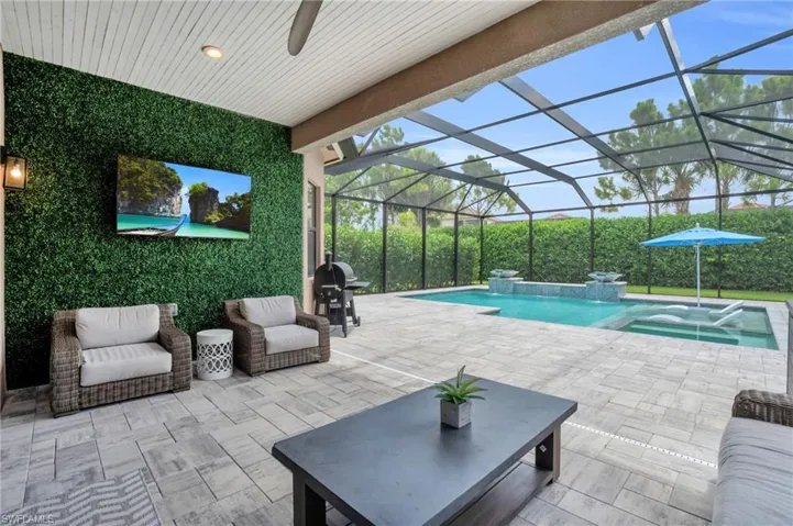 View of swimming pool with a patio area, a lanai, an in ground hot tub, and grilling area