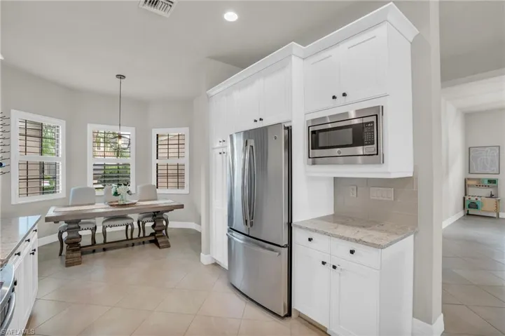 Kitchen featuring appliances with stainless steel finishes, light stone countertops, and light tile floors