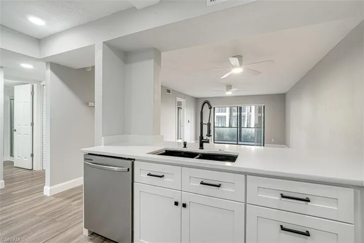 Kitchen featuring dishwasher, light countertops, light wood-style floors, white cabinets, and a ceiling fan