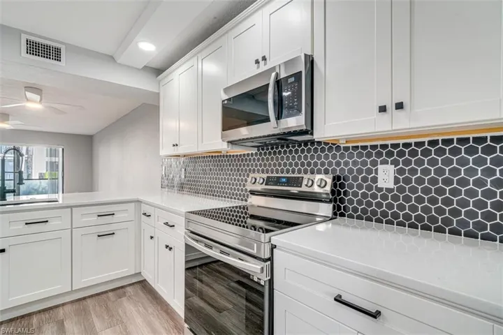Kitchen featuring appliances with stainless steel finishes, light wood-style flooring, white cabinetry, tasteful backsplash, and recessed lighting