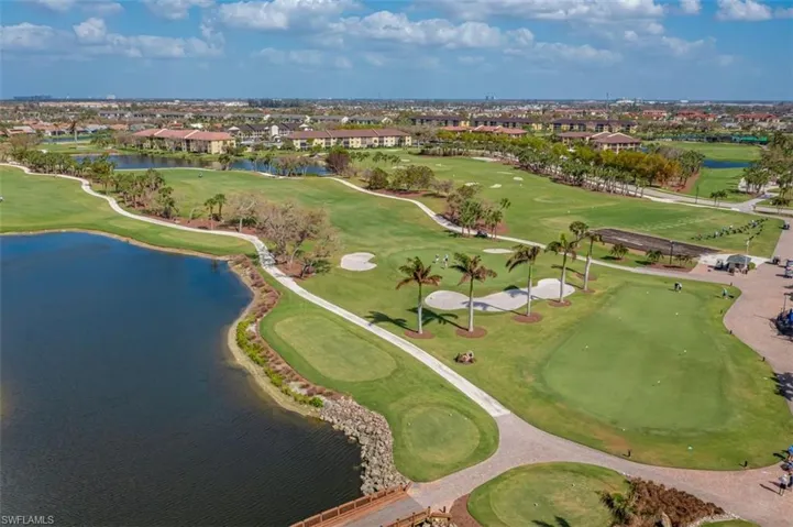 Aerial view of property's location featuring a nearby body of water, a golf course, and nearby suburban area