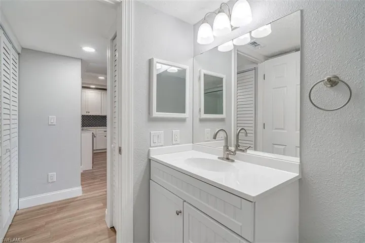 Bathroom with vanity, wood finished floors, and a textured wall