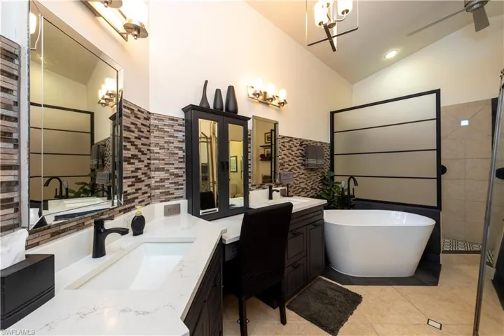 Master Bathroom featuring a freestanding tub, two vanities, spacious shower and vaulted ceiling