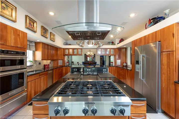 Kitchen featuring island with 6 burner cooktop and prep sink