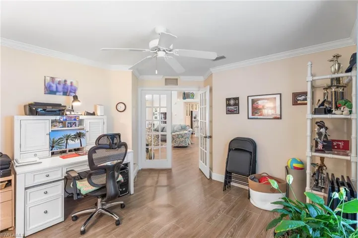 Office area featuring french doors, crown molding, baseboards, light wood finished floors, and a ceiling fan