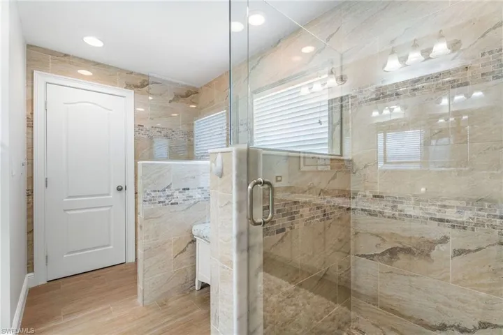 Bathroom featuring a stall shower, wood finished floors, and tile walls
