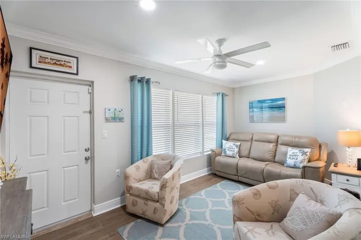 Living area featuring crown molding, ceiling fan, wood finished floors, baseboards, and recessed lighting