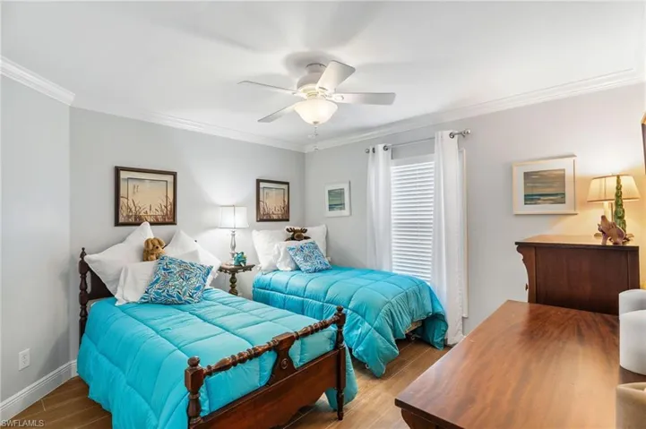 Bedroom with wood finished floors, crown molding, baseboards, and a ceiling fan