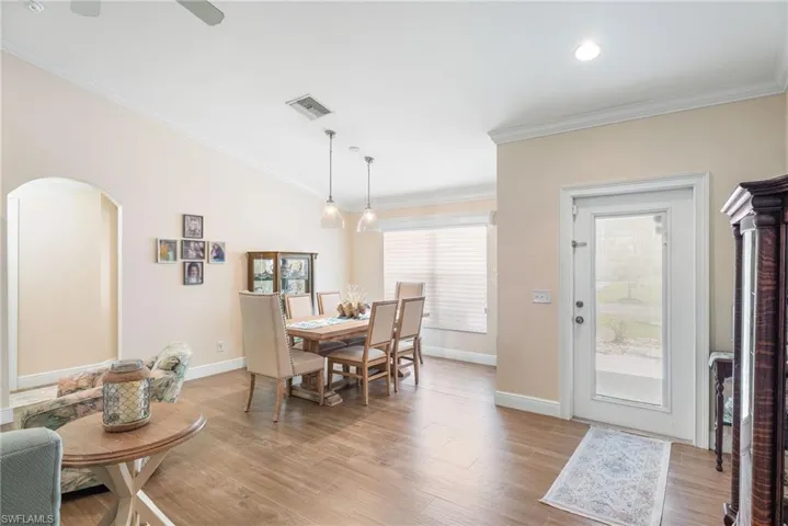 Dining area with arched walkways, baseboards, light wood finished floors, crown molding, and vaulted ceiling