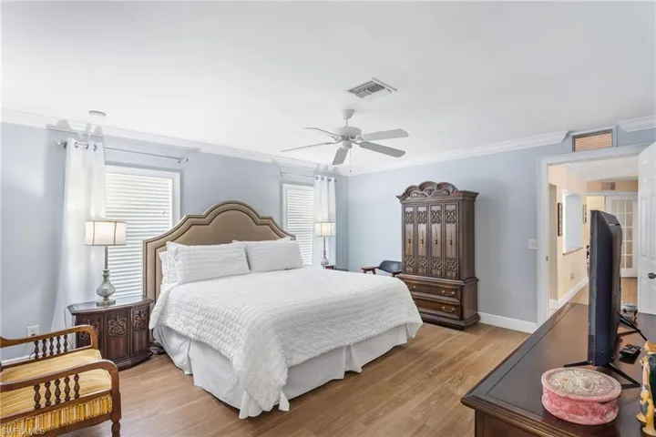 Bedroom with ornamental molding, light wood-style flooring, ceiling fan, and baseboards