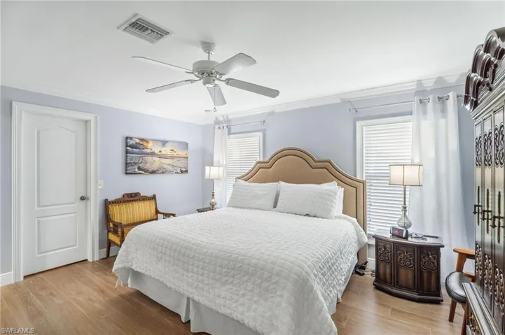 Bedroom with ornamental molding, light wood-type flooring, and a ceiling fan