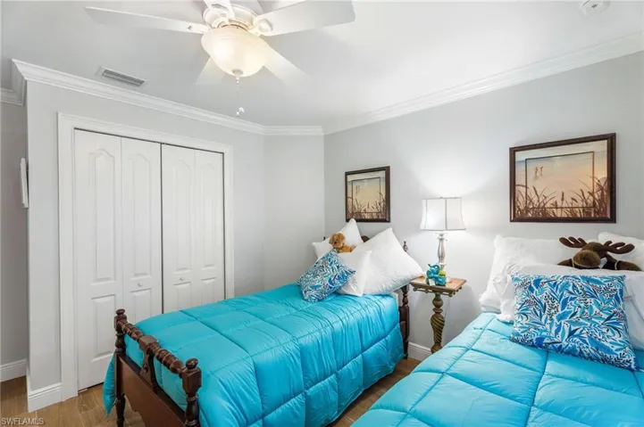 Bedroom with wood finished floors, a closet, baseboards, crown molding, and ceiling fan