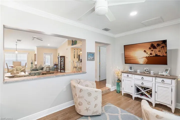 Living area with ceiling fan, baseboards, ornamental molding, light wood-style flooring, and recessed lighting
