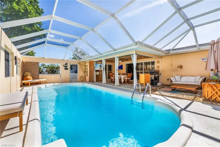 Swimming pool featuring outdoor lounge area, a patio, glass enclosure, and a grill