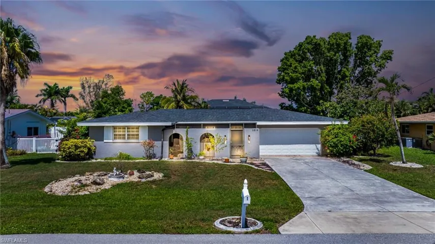 Ranch-style house with a lawn, an attached garage, driveway, and stucco siding