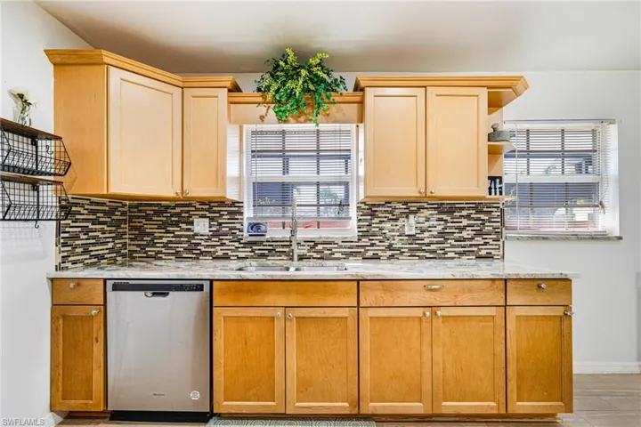 Kitchen featuring dishwasher, open shelves, tasteful backsplash, and light brown cabinets