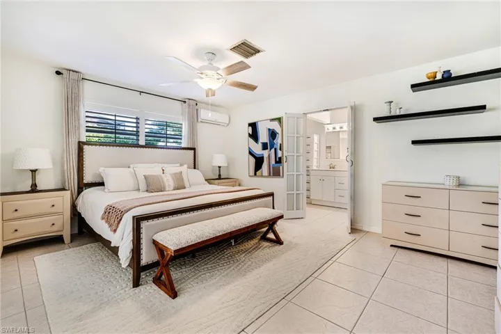 Bedroom featuring light tile patterned flooring, a wall unit AC, ceiling fan, and french doors