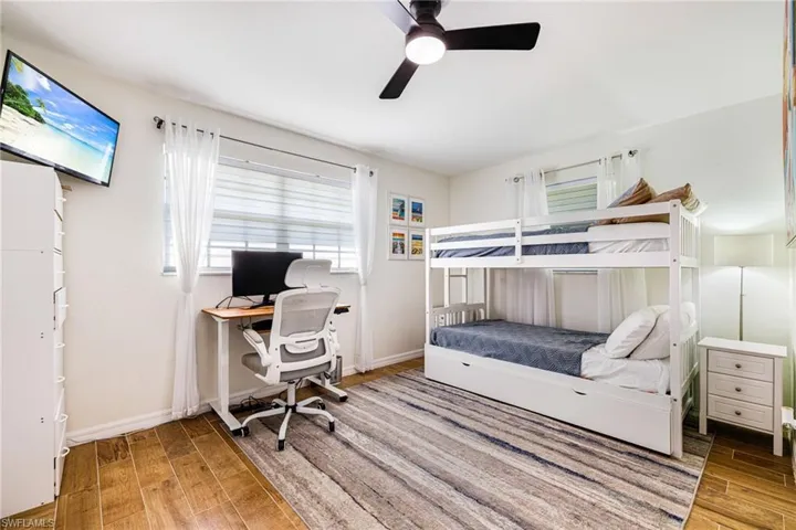Bedroom featuring wood finished floors, a ceiling fan, and an office area