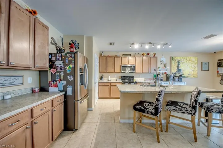 Kitchen featuring appliances with stainless steel finishes, a breakfast bar area, light tile patterned floors, and a center island with sink