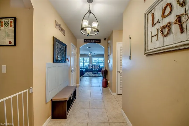 Hallway with a chandelier, light tile patterned flooring, and arched walkways