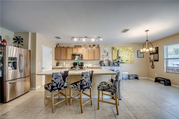 Kitchen with stainless steel appliances, light tile patterned floors, a center island with sink, and a chandelier