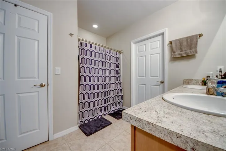 Full bathroom with tile patterned floors, double vanity, and curtained shower