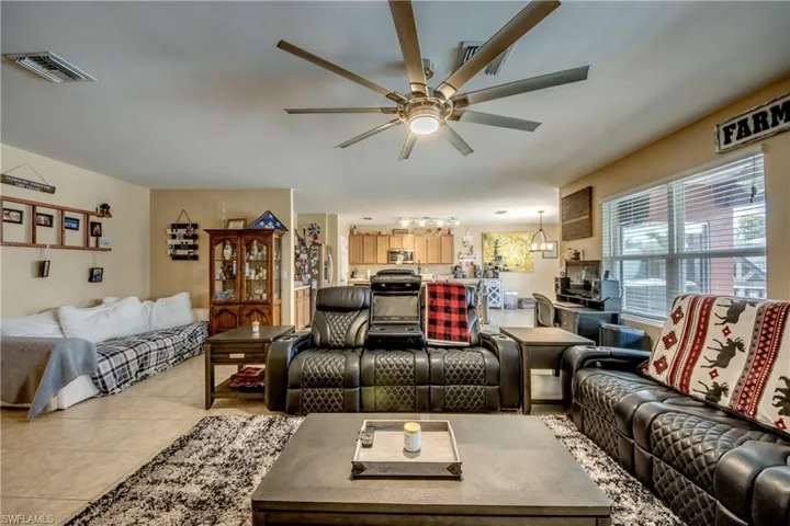 Living room featuring ceiling fan, light tile patterned floors, and a chandelier