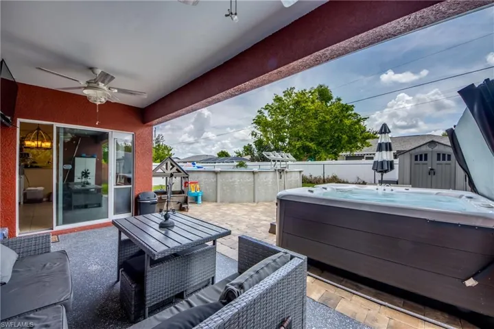 View of patio / terrace with a hot tub, a ceiling fan, a shed, area for grilling, and an outdoor living space