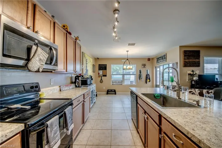 Kitchen with black appliances, brown cabinetry, and light countertops
