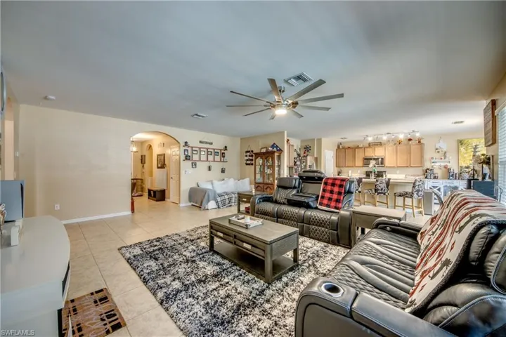Living area featuring arched walkways, a ceiling fan, and light tile patterned floors