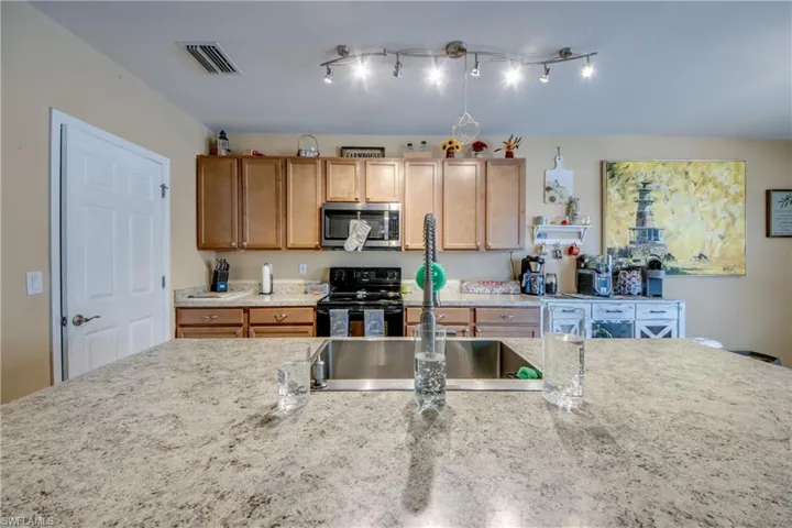 Kitchen featuring stainless steel microwave, black / electric stove, and light stone countertops