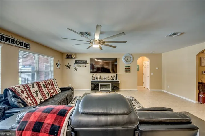 Tiled living room with arched walkways and a ceiling fan