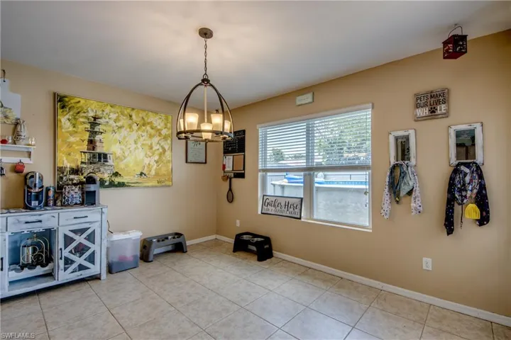 Tiled dining space featuring a chandelier and baseboards